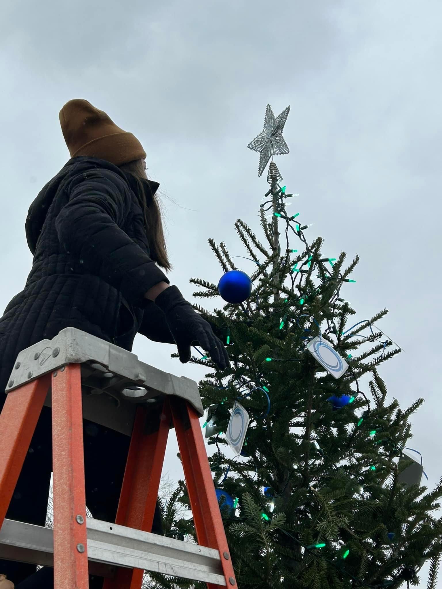 A person putting the star on top of a tree